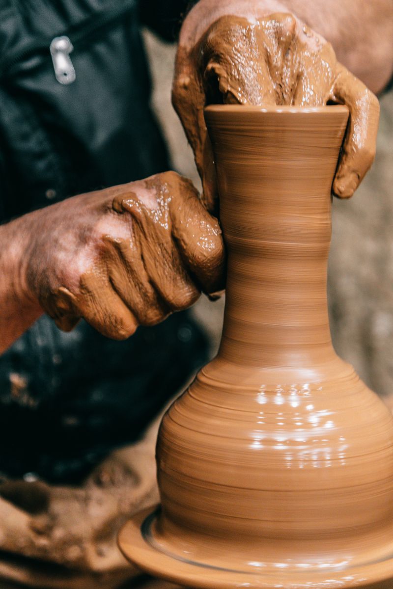 Hands shaping wet clay on a pottery wheel